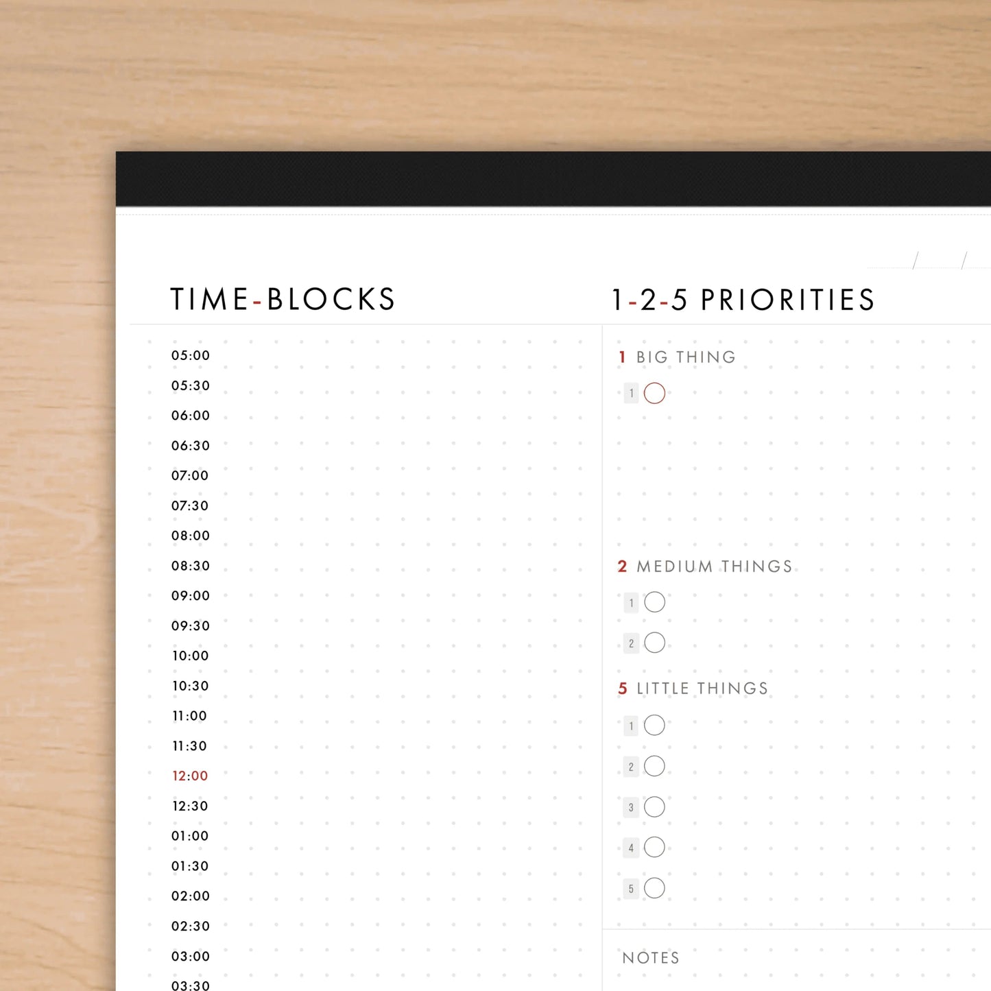 Time-blocks and priorities schedule on a white sheet with black border, placed on a wooden surface.