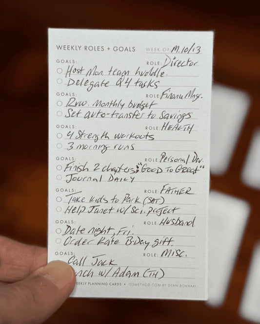 Weekly roles and goals card held by a hand with a blurred background