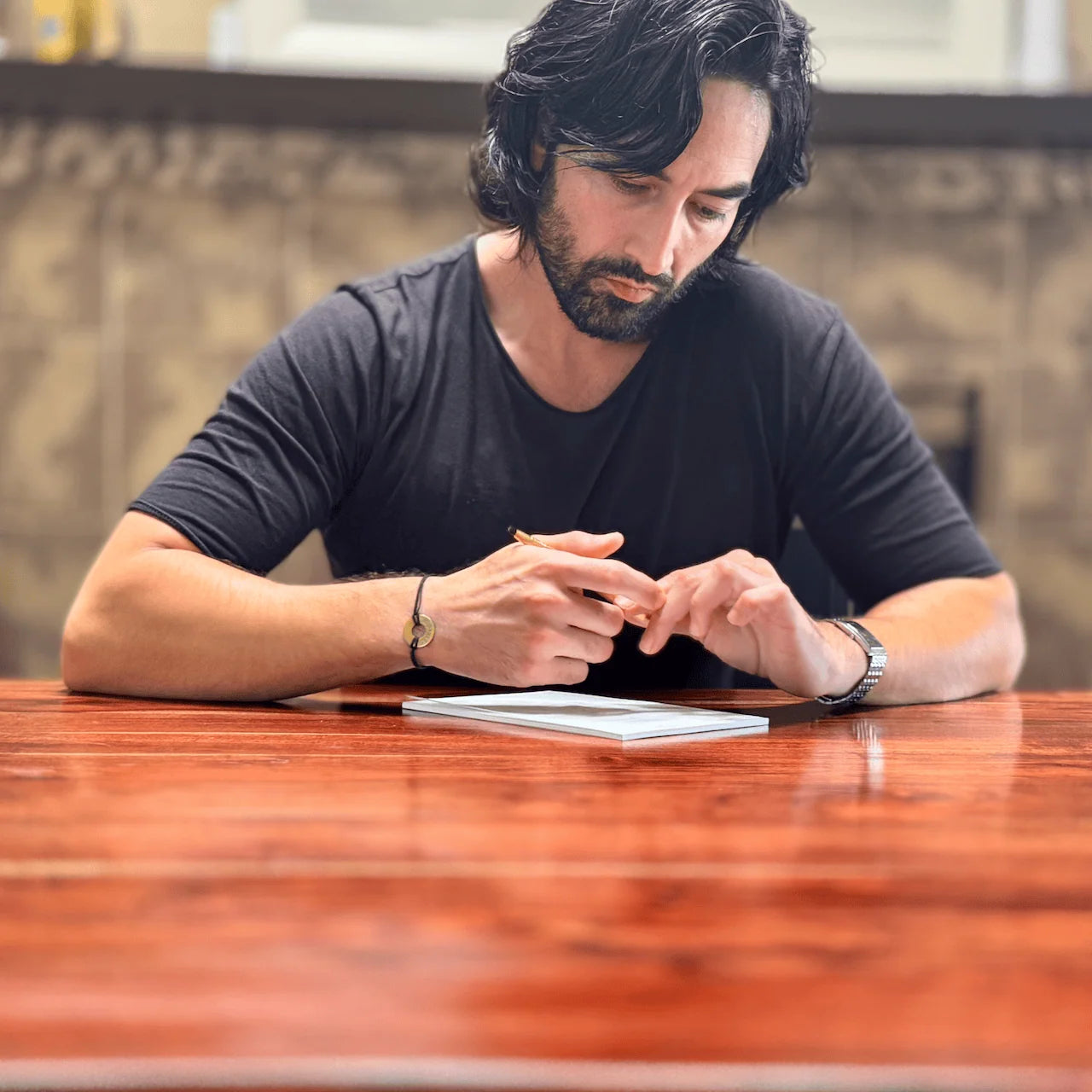 Dean Bokhari sitting at a wooden table with a 1-2-5 Time Blocking Planner, wearing a black shirt.