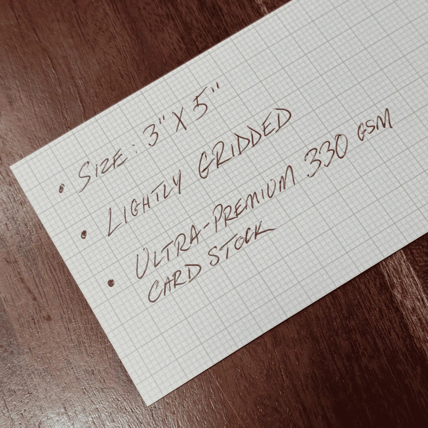 Sheet of lighty gridded ultra-premium card stock on a wooden surface