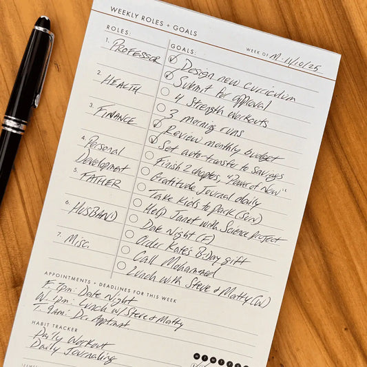 Weekly Roles and Goals Planning Pad with a pen on a wooden table