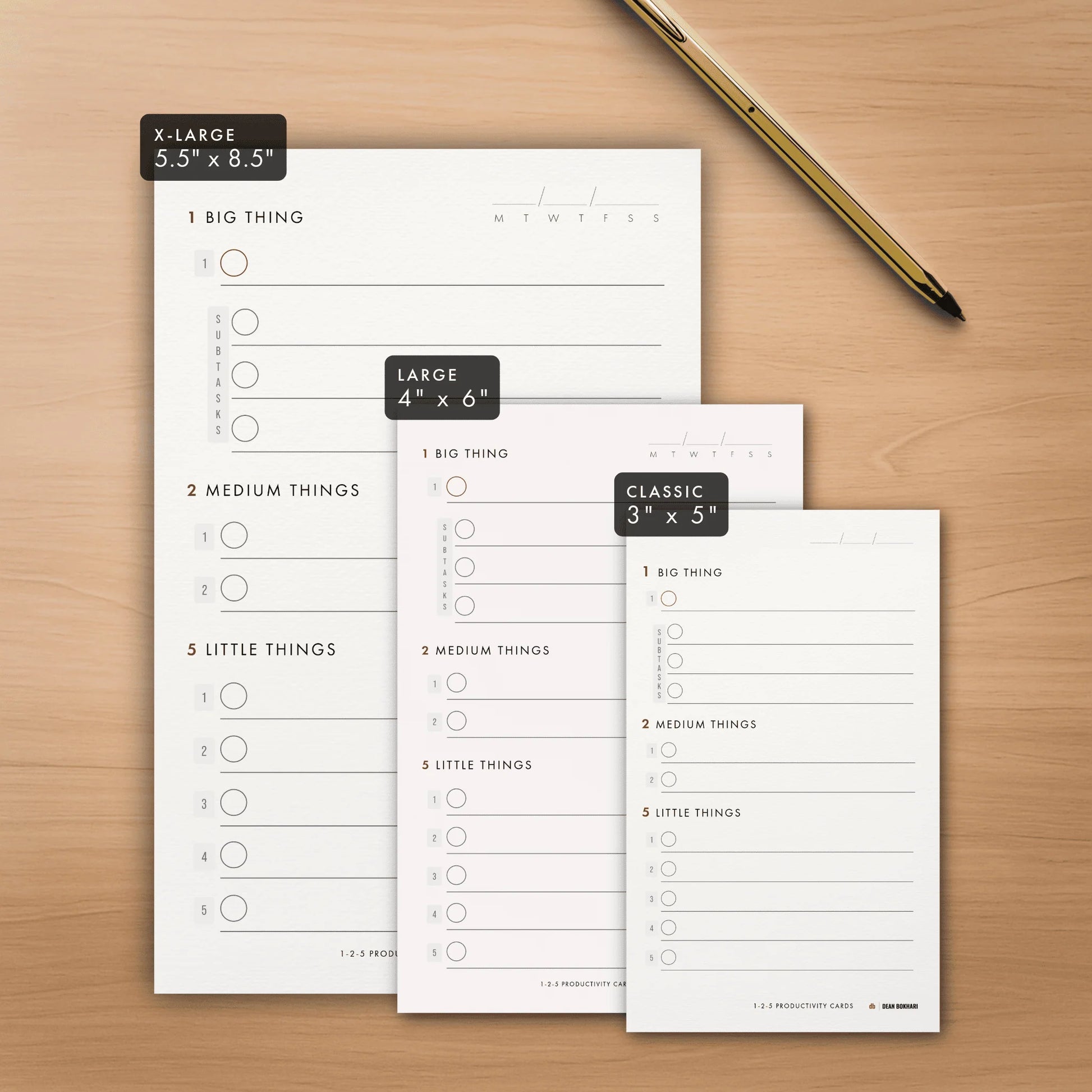 A size comparison of X-Large, Large, and Classic daily productivity cards next to a gold pen
