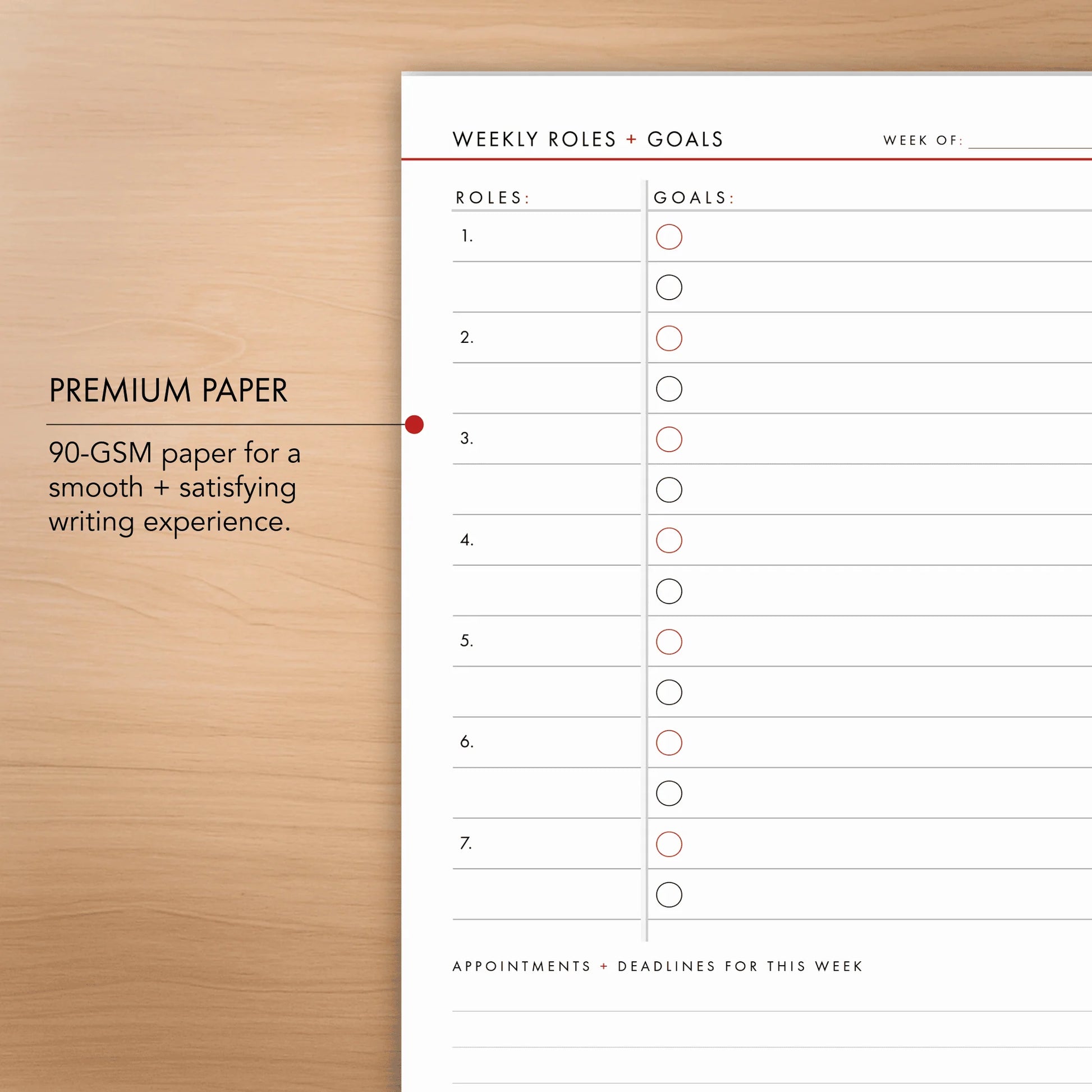 Weekly roles and goals planner sheet on a wooden surface with text about premium paper quality.