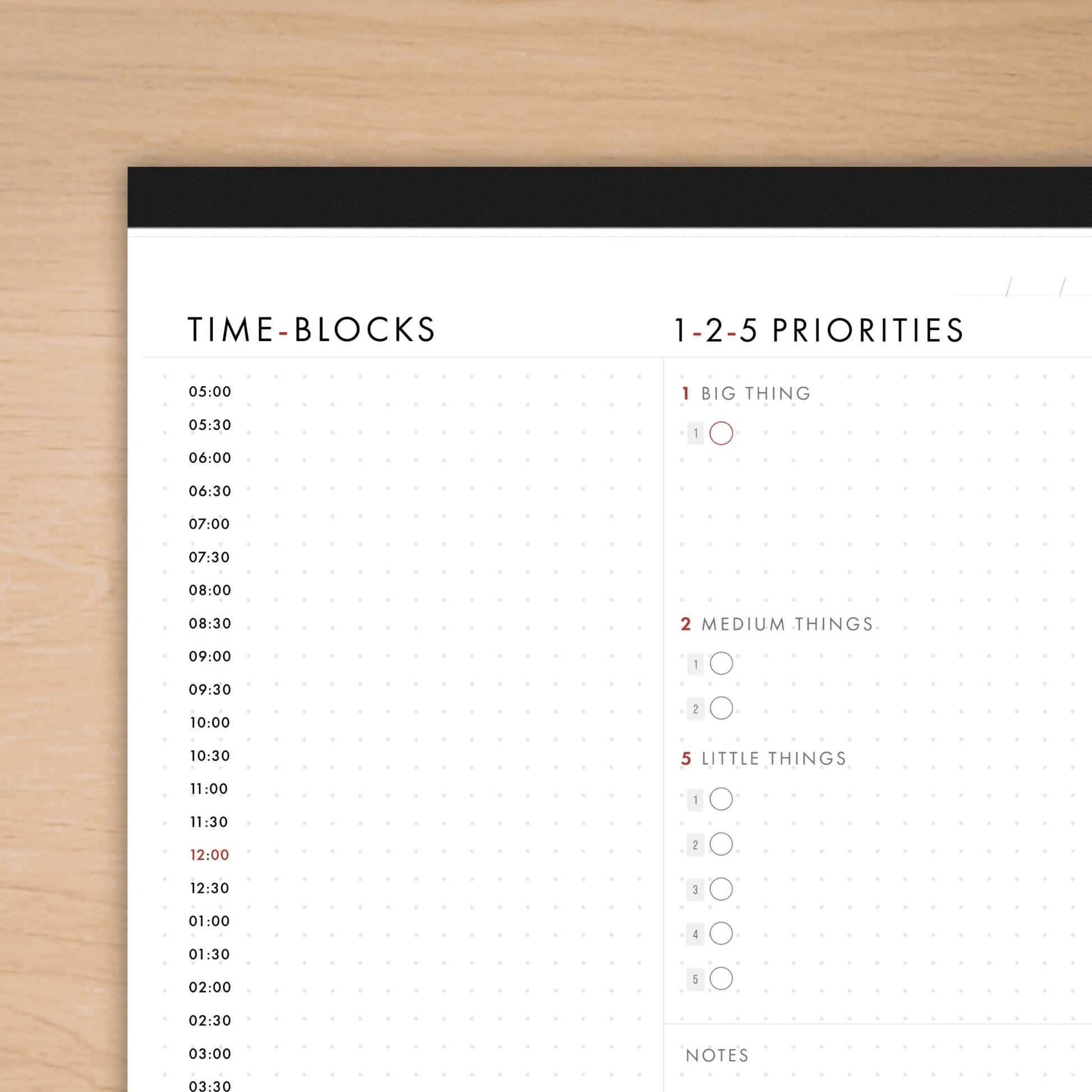 Time-blocks and priorities schedule on a white sheet with black border, placed on a wooden surface.