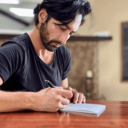 Author_Dean_Bokhari_writing_on_a_premium_125Method™_notepad_at_a_table_in_an _indoor_setting